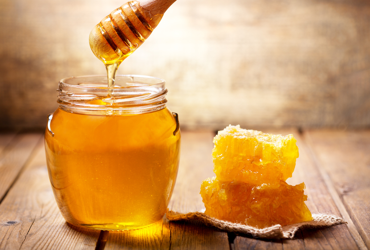pouring honey into jar of honey